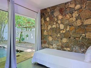 a bedroom with a stone wall and a bed next to a window at Native Lodge et Spa in Mahébourg