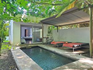 a pool with a bed next to a house at Native Lodge et Spa in Mahébourg