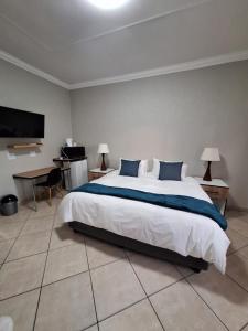 a bedroom with a large bed and a desk at Rams Blissful Guest House in Rustenburg +22 photos