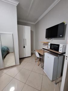 a living room with a table and a tv on the wall at Rams Blissful Guest House in Rustenburg