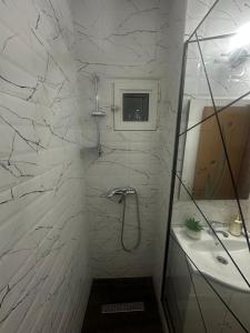 a white bathroom with a shower and a sink at Dragasani Cozy Apartament in Drăgăşani +35 photos
