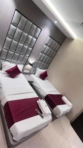 two beds in a hotel room with red pillows at Hotel Abrol in Mumbai