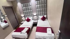 two beds in a small room with red pillows at Hotel Abrol in Mumbai
