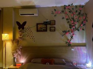 a bedroom with a bed with a tree on the wall at AN BÌNH Home in Hai Phong