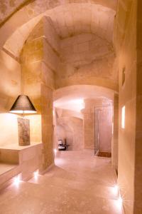 
a large room with a stone wall and a clock on the wall at Palazzo Gattini Luxury Hotel in Matera
