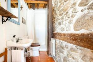 a bathroom with a sink and a stone wall at Casa Valle del Lozoya in Rascafría +37 photos