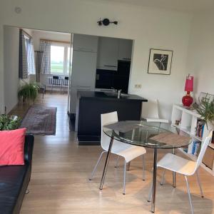 a living room with a table and chairs and a kitchen at De tuin van Agatha in Kortessem
