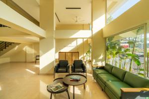 a lobby with a green couch and two chairs at Minimalist Panjim in Panaji