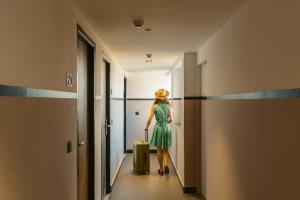 a woman in a green dress walking down a hallway with a suitcase at Minimalist Panjim in Panaji