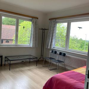 a bedroom with two chairs and a bed and two windows at De tuin van Agatha in Kortessem