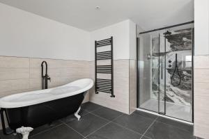 a bathroom with a black and white tub and a shower at Pilgrim Suite - Sea View - Free Wi-Fi in Brixham +9 photos