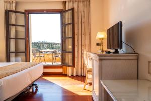 a bedroom with a bed and a television and a balcony at Hotel Conde Ansúrez in Valladolid