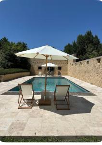 two chairs and an umbrella next to a swimming pool at Chapelle Blóm in Nougaroulet