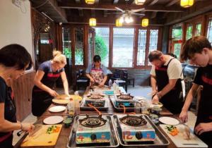 a group of people standing around a table with food at Yangshuo Eden's Social Guesthouse - cozy garden courtyard & fresh craft coffee & night beers & outdoor activities in Yangshuo