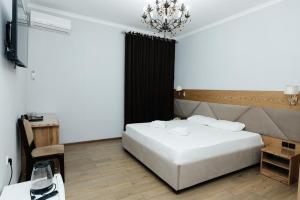 a bedroom with a white bed and a chandelier at ALCAZAR in Atyrau