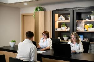 three people sitting at a table with a laptop at Ensana Thermal Aqua in Hévíz +28 photos