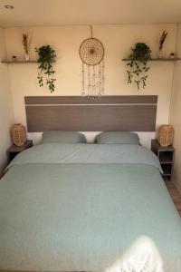 a bedroom with a green bed with two plants on the wall at Domki Na Ranczo in Gniezno