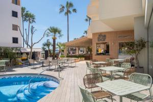 a patio with tables and chairs next to a pool at Cabot Cap de Mar Spa in Cala Bona