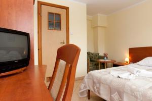 a bedroom with a bed and a table with a television at Dom Gościnny Basia in Niechorze