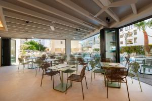 a restaurant with tables and chairs and windows at Cabot Cap de Mar Spa in Cala Bona