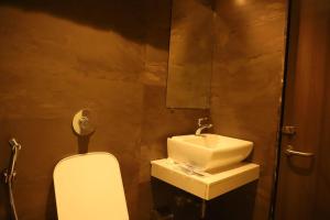 a bathroom with a sink and a toilet and a mirror at Hotel Abrol in Mumbai