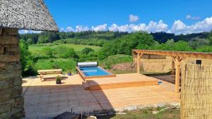 a backyard with a swimming pool and a wooden deck at Les chaumières de Brameix in Neuvic