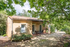 a cottage with a table and chairs on a driveway at Gîte Le Mazet Des Campanes in Saint Alban Auriolles