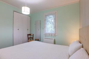 a bedroom with a white bed and a window at Gîte Le Mazet Des Campanes in Saint Alban Auriolles