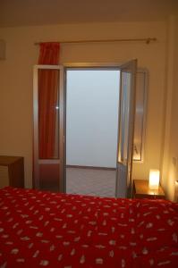 ガリポリにあるTramonto -Appartamenti OltreMare- Lido Conchiglie Gallipoliのベッドルーム1室(赤いベッド1台、ガラスのスライドドア付)