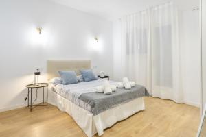 a white bedroom with a large bed with blue pillows at Myholidayshome in Palamós