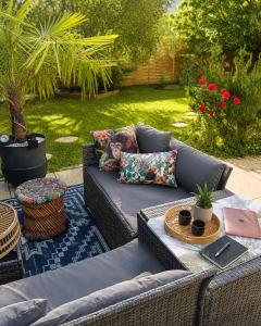 a wicker couch with pillows on a patio at L'océane in Saint-Maurice-de-Beynost