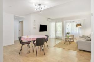 a white living room with a pink table and chairs at Myholidayshome in Palamós