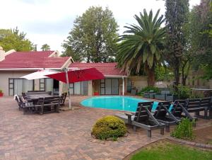 a patio with chairs and an umbrella and a pool at Vukani Holdings Group in Vanderbijlpark