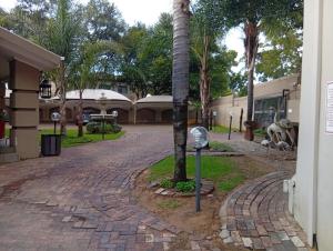 a parking meter next to a palm tree on a brick road at Vukani Holdings Group in Vanderbijlpark