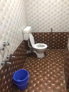 a bathroom with a toilet and a blue bucket at HOTEL SHIVA in Guwahati
