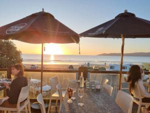 two women sitting at a table with a view of the beach at The Hideaway in Raumati Beach