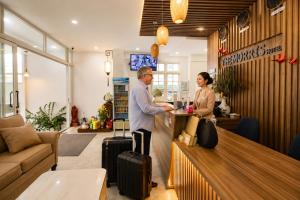 a man and a woman standing at a counter with luggage at The Morris City Central Boutique in Da Lat