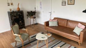 a living room with a brown leather couch and chairs at De Notelaar in Kortessem