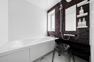 a bathroom with a white tub and a mirror at Silvale in Kami-furano