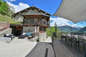 a building with a balcony with a table and chairs at La Ferme D'aurélie in Montvalezan