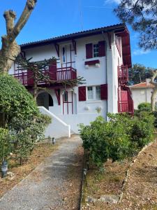 ein weißes Haus mit roten Balkonen und einer Auffahrt in der Unterkunft Duplex studio Moulleau proche plage avec chambre en mezzanine in Arcachon