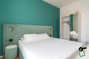 a bedroom with a white bed and a blue wall at Hotiday Castiglioncello Suite in Castiglioncello
