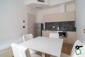 a white kitchen with a white table and chairs at Hotiday Castiglioncello Suite in Castiglioncello