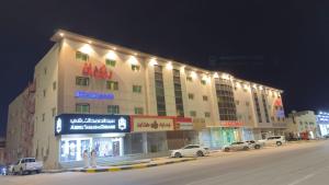 a large building with cars parked in front of it at رؤوم إن للشقق المخدومة -المجمعة- Raoum Inn Serviced Apartments-Majmaa in Al Majma'ah