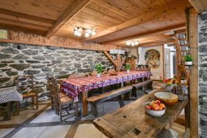 a dining room with wooden ceilings and a stone wall at La Ferme D'aurélie in Montvalezan