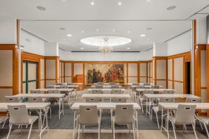 a dining room with tables and chairs and a painting at Ensana Thermal Hévíz in Hévíz