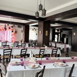 a restaurant with white tables and chairs and pink decorations at Pensiune Restaurant Indus in Ocna Sibiului