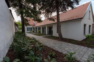 a white house with a red roof and a walkway at Jancsó Apartman in Dunaföldvár