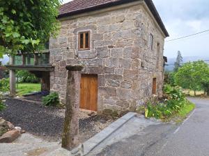 a stone house with a wooden door on the side at Casa de mestre 2 in Freijo +5 photos