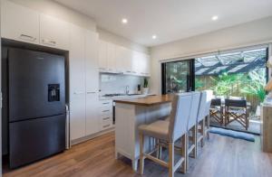 a kitchen with a black refrigerator and white cabinets at Seaside Luxe at Vila Morava in Rosebud